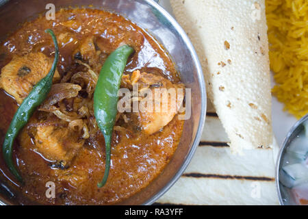 Knoblauch Chili Huhn. Gebeizt Hühnerfleisch curry mit ganzen Chili garnieren Reis, Gurke und poppadom Minze Joghurt dip Stockfoto