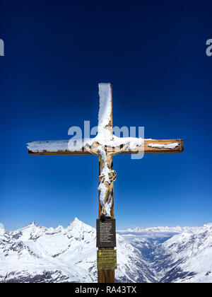 Schnee bedeckt Kreuz mit einer hölzernen Figur von Jesus Christus am Gipfel des Klein Matterhorn mit Materie Tal im Hintergrund, Zermatt, Switzerlan Stockfoto