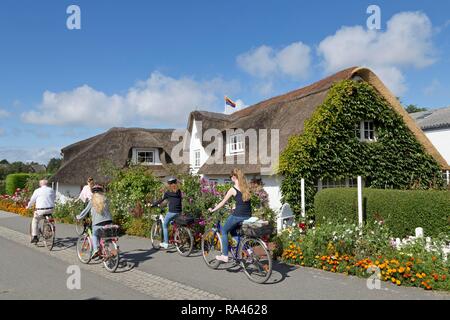 Radfahrer vor Thatched House, Nebel, Amrum, Nordfriesland, Schleswig-Holstein, Deutschland Stockfoto