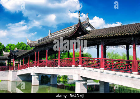 Ein Chinesischer Pavillon und überdachte Brücke über den kleinen See innerhalb der Luzhi antike Stadt landschaftlich reizvollen Gegend an einem sonnigen Tag in Wuzhong China. Stockfoto