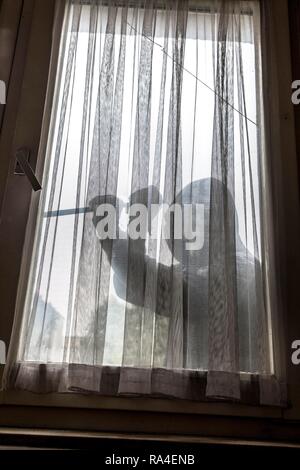 Symbol Bild apartment Einbruch, Täter versucht, in eine Wohnung zu brechen, nimmt ein Fenster mit einem Werkzeug Stockfoto