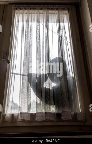 Symbol Bild apartment Einbruch, Täter versucht, in eine Wohnung zu brechen, nimmt ein Fenster mit einem Werkzeug Stockfoto