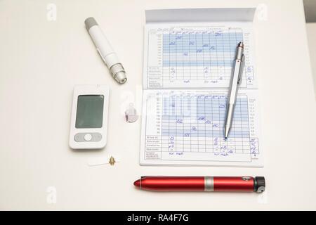 Diabetes, links Blutzuckermessgeräte, Teststreifen und Stechhilfe, Insulinpen, Blutglukose Tagebuch, Deutschland Stockfoto