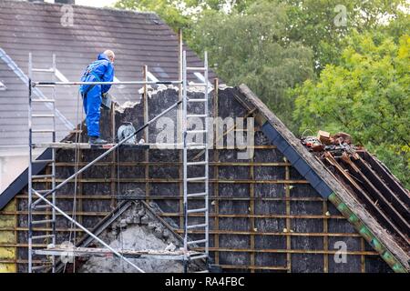 Abriss von einem älteren Wohngebäude, hier neue Mietwohnungen gebaut, Essen, Arbeiter in Schutzanzug demontieren Stockfoto