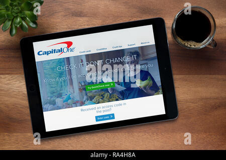 Die Website von Capital One ist auf einem iPad Tablet gesehen, auf einer hölzernen Tisch zusammen mit einem Espresso und einem Haus Anlage (nur redaktionelle Nutzung).