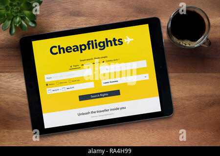 Die Website von cheapflights ist auf einem iPad Tablet gesehen, auf einer hölzernen Tisch zusammen mit einem Espresso und einem Haus Anlage (nur redaktionelle Nutzung). Stockfoto