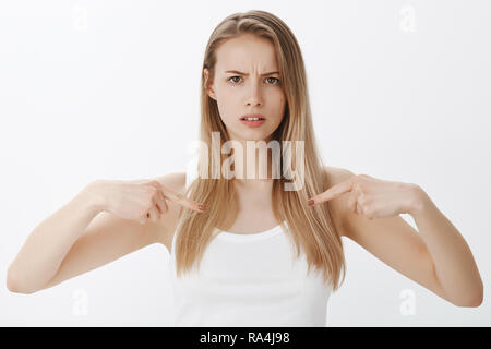 Intensive Mädchen mit ernsten Gesicht an sich, als Fragen stellen, und sich nicht sicher sind, mit gerunzelter Stirn die Grimasse warten auf Stellungnahme per Email über Ihr Outfit über grauer Hintergrund posiert Stockfoto