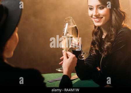 Lächelnd attraktive Frauen mit klirren Gläser Champagner am Poker Tisch im Casino Stockfoto