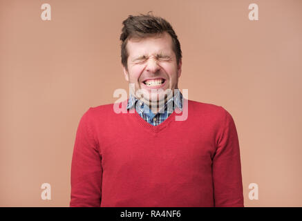 Guy grinst Kamera, zeigt weiße Zähne, schließt eyeswaiting für Geschenk Stockfoto