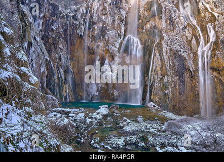 Gefrorene großen Wasserfall, in Schnee und Eis in Grün pool Wasser fallen. Blick auf die Horseshoe Klippen. Szene in Nationalpark Plitvice Stockfoto