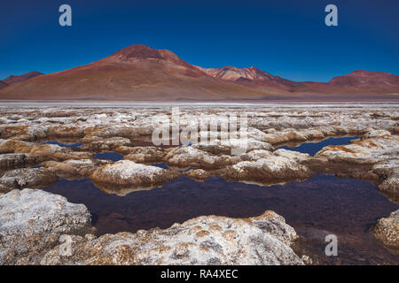 Getrocknete Salzlagerstätten in Siloli, Bolivien, spiegelt sich in dem seichten Wasser der Wanne mit Bergspitzen im Hintergrund Stockfoto