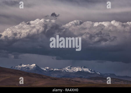 Hevy dunkle Gewitterwolken über steile schneebedeckte Berge in der Ferne. Landschaft der Anden, Südamerika Stockfoto