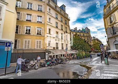 Ein Mann parkt ein Motorroller in der Nähe einer belebten Restaurant, während ein anderer Mensch sieht auf seinem Telefon, entlang der Rue de Douai, in ThePigalle Gegend von Paris Stockfoto