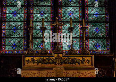 Kerzen in Messing candler Inhaber Alter mit einer atemberaubenden blauen und grünen Glasfenster in der Kathedrale Notre Dame, Paris Stockfoto