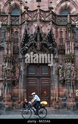 Ein Radfahrer vorbei an der Kathedrale Notre-Dame zu Straßburg, Elsass, Frankreich Stockfoto