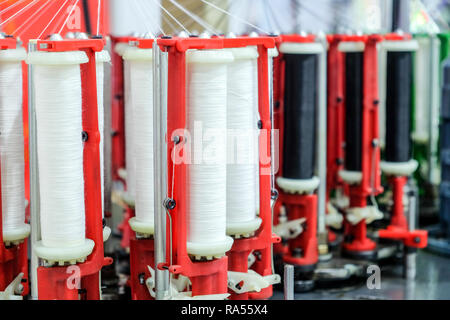 Selektiver Fokus weiß Garn im Garn Röhren von Industrienähmaschinen. Stockfoto