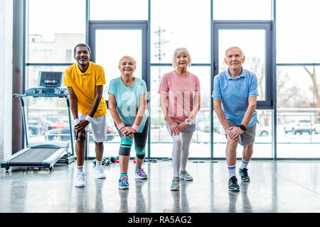 Freundliche senior multiethnischen Sportler synchrone Stretching im Fitnessstudio Stockfoto