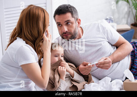 Mutter, Arzt und Vater Kontrolle der Temperatur von kranken Tochter im Schlafzimmer Stockfoto