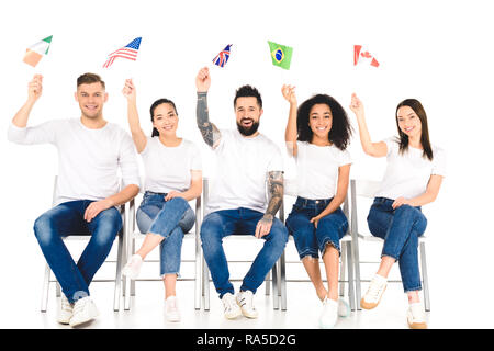 Multikulturelle Gruppe von Menschen sitzen auf Stühlen mit Fahnen der verschiedenen Länder über den Köpfen isoliert auf weißem Stockfoto