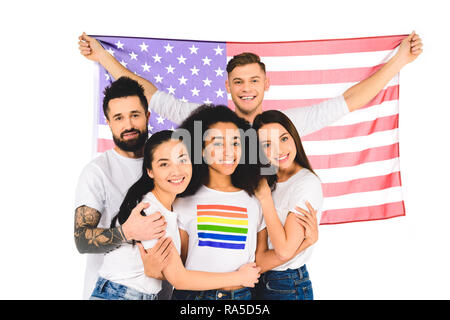 Multiethnische Gruppe junger Menschen Lächeln und Umarmungen während die Flagge der USA isoliert auf weißem Stockfoto