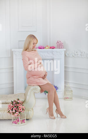 Schwangere Frau sitzt auf einem Sofa zu Hause Stockfoto