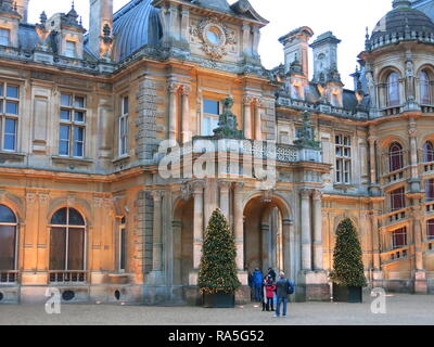 Besucher ankommen am Eingang Waddesdon Manor, die durch zwei grosse Weihnachtsbäume in Lichterketten abgedeckt flankiert wird Stockfoto