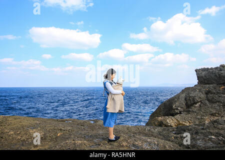 Asiatische Mutter mit ihrem Baby am Kap Zanpa Okinawa Japan Stockfoto