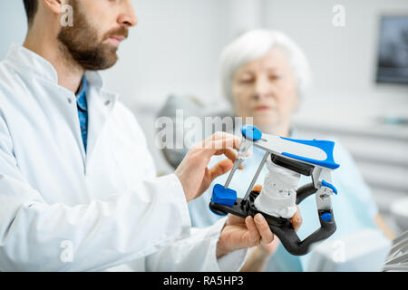 Zahnarzt mit künstlichen Kiefer während der Konsultation mit älteren Frau, die in der Zahnarztpraxis Stockfoto