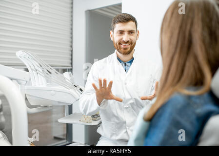 Stattliche Zahnarzt im Gespräch mit Frau Patienten während der ärztlichen Beratung in der Zahnarztpraxis Stockfoto