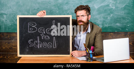 Willkommen zurück. Lehrer begrüßt neue Schülerinnen und Schüler der Bildungseinrichtung eingeben. Zu Beginn des neuen Schuljahres im September. Lehrer oder Schulleiter begrüßt mit blackboard Inschrift zurück in die Schule. Stockfoto