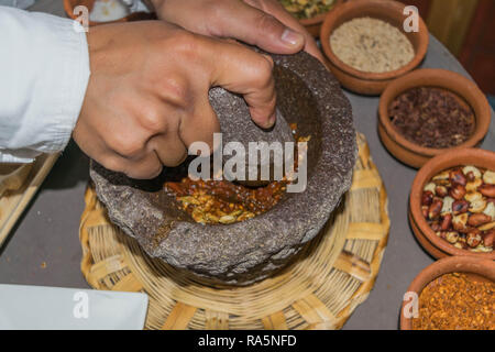 Hand vorbereiten, Salsa in einem Mörser und Stößel, mit vielen kleinen Terra-Cotta Schüsseln mit Zutaten gefüllt, auf einer großen Platte, in Oaxaca, Mexiko Stockfoto