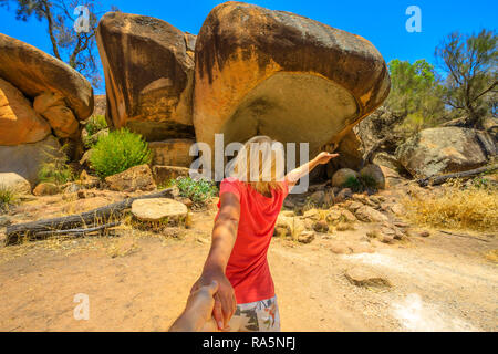 Folgen Sie mir, Frau, Hände halten in Hippo's Yawn, ein Hippo-geformten Felsen in der Nähe der Wave Rock in Hyden, australische Outback, Western Australia. Konzept der Reise von touristischen Reisenden, der Mann mit der Hand. Stockfoto