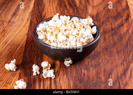 Salz Popcorn auf dem Holztisch. Popcorn in eine Schüssel geben. Einen Film mit Popcorn. Kopieren Sie Platz. Pop Corn. Stockfoto