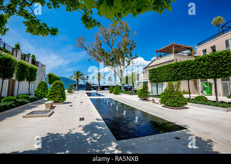 TIVAT MONTENEGRO - September 10, 2017: Grüner Baum wirft Schatten über Fußgängerzone in der Nähe von Brunnen im Luxus Tivat Damm, Montenegro, Szene Stockfoto