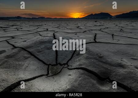 Risse, ausgetrockneten Boden mit kleinen Wasser- und Allgäuer Alpen im Hintergrund bei Sonnenaufgang, Forggensee, Füssen, Ostallgäu Stockfoto