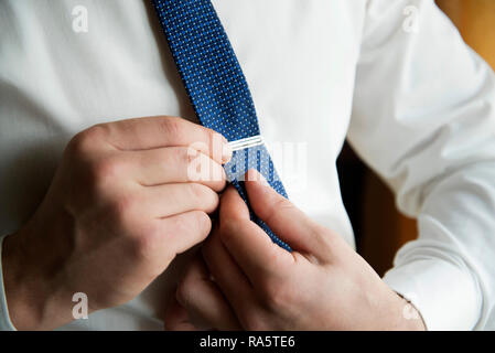 Menschen setzen auf Manschettenknöpfe, wie er in der formalen Verschleiß gekleidet wird. Für den Bräutigam. Mann im Anzug seine Krawatte zur Festsetzung. Montag morgen Arbeitstag. Stockfoto