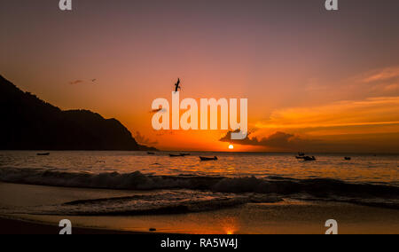 Tobago, West Indies, Karibik. Schönen Sonnenuntergang über dem Meer im Fischerdorf Castara mit Seevögeln und pelikanen Tauchen in den Ozean. Stockfoto