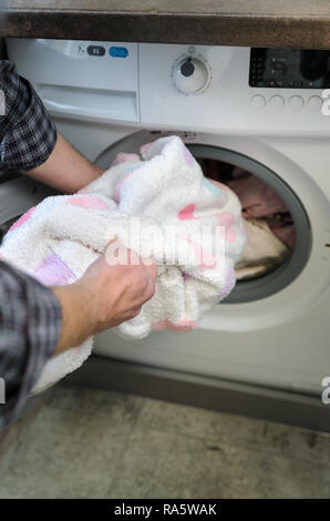 Mann nimmt die Dinge mit der Waschmaschine gewaschen. Stockfoto