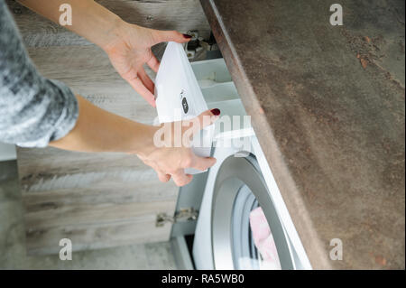 Frauen Hände halten einen Behälter mit Waschmittel aus der Waschmaschine. Stockfoto