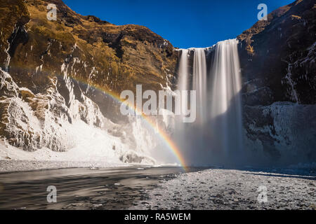 Skógafoss, einem wunderschönen Wasserfall mit einem Regenbogen im Spray, entlang des Flusses Skógá und Fallen über ehemalige Klippen, entlang der Südküste Islands i Stockfoto