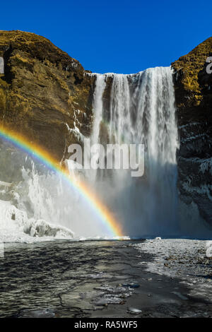 Skógafoss, einem wunderschönen Wasserfall mit einem Regenbogen im Spray, entlang des Flusses Skógá und Fallen über ehemalige Klippen, entlang der Südküste Islands i Stockfoto