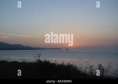 Goldene Stunde Sonnenuntergang mit Blick auf die Insel Korfu. Sonnenuntergang am Strand in der Nähe von Ksamil Saranda, Albanien. Stockfoto