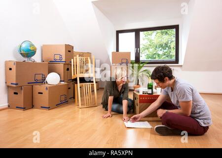 Junges Paar sitzt in einem leeren Raum in eine neue Wohnung und Lesen der Lease Stockfoto