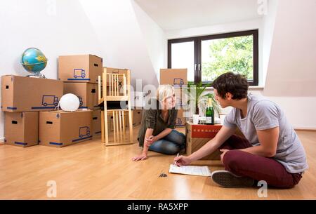 Junges Paar sitzt in einem leeren Raum in eine neue Wohnung und Lesen der Lease Stockfoto