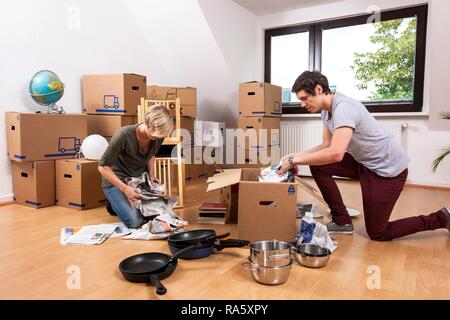 Junges Paar in einen leeren Raum in eine neue Wohnung Auspacken der ersten Boxen Stockfoto