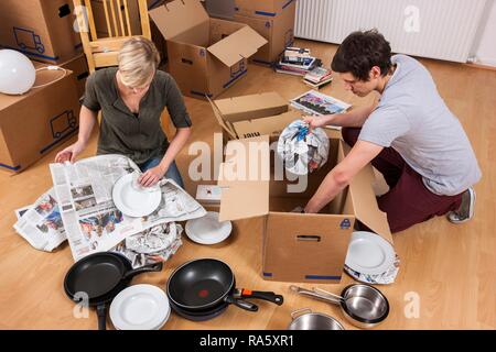 Junges Paar in einen leeren Raum in eine neue Wohnung Auspacken der ersten Boxen Stockfoto