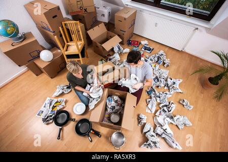 Junges Paar sitzt in einem leeren Raum in eine neue Wohnung Kisten auspacken Stockfoto
