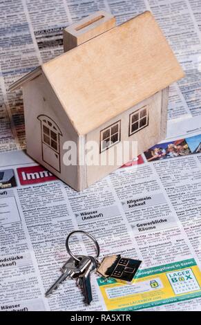 Eine kleine hölzerne Haus und zwei Schlüsseln mit einem Metall Schlüsselanhänger wie ein Haus aussieht, auf den Immobilien Seite einer deutschen Tageszeitung Stockfoto