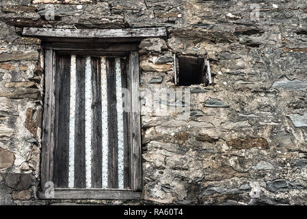 Alte mittelalterliche Burg Stein Wand Textur unter natürlichem Licht mit Brettern vernagelt die Fenster Hintergrund Stockfoto