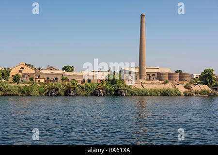 Blick über den großen Fluss Nil in Ägypten durch ländliche Landschaft mit industriellen Zuckerrohr Fabrik mit Schornstein Stockfoto